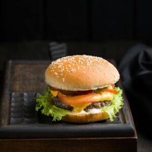 Close-up of a delicious cheeseburger with lettuce, tomato, and cheese on a sesame seed bun.